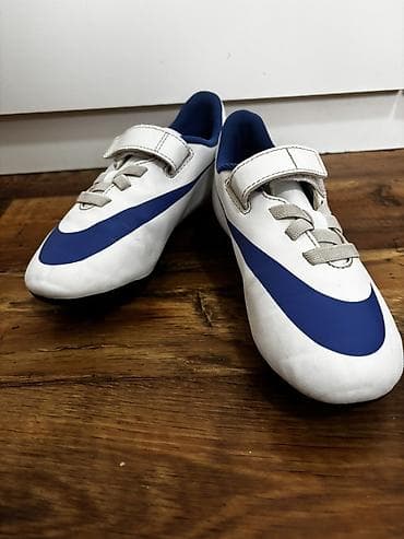 Dečje fudbalske kopačke Nike – bela osnova sa plavim Swoosh logom. -
