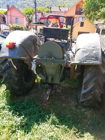 Robusni poljoprivredni traktor sive boje, opremljen širokim gumama sa