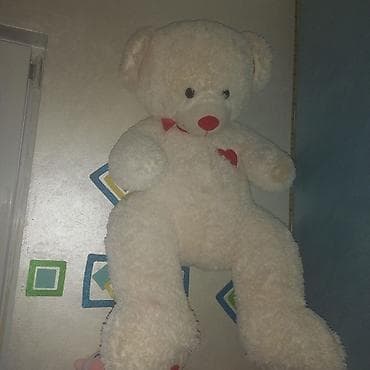 Veliki plišani meda, bele boje sa crvenim detaljima na nosu, mašnici i