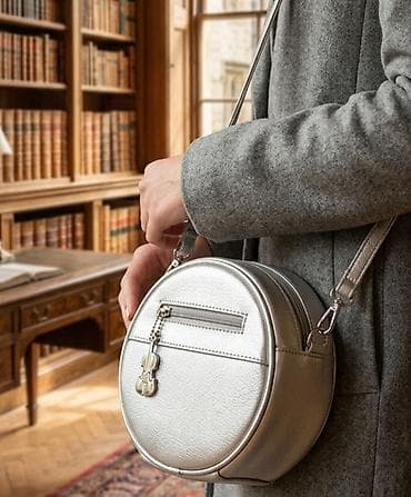 Okrugla ženska torbica preko ramena, metalik srebrne boje. -