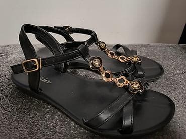 Crne sandale sa ukrasnim detaljima u obliku cvetova. Imaju kaiščić oko