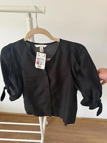 Crna ženska bluza sa dugmićima sprijeda. Model sa blago naborenim
