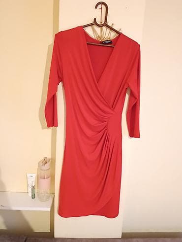 Elegantna crvena haljina sa preklopljenim V-izrezom. Model do kolena