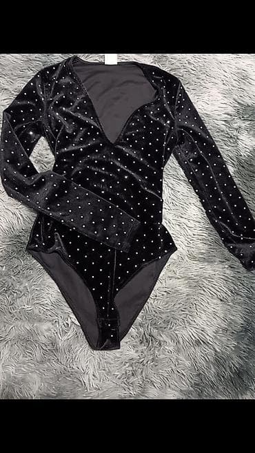 Crni velvet bodi sa dugim rukavima i dubljim V izrezom. Materijal je