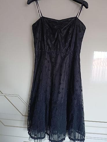 Crna haljina sa tankim bretelama, dužine do kolena. Gornji deo haljine