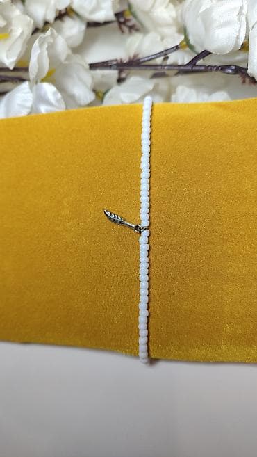 Delikatna narukvica od sitnih belih perlica sa metalnim priveškom u