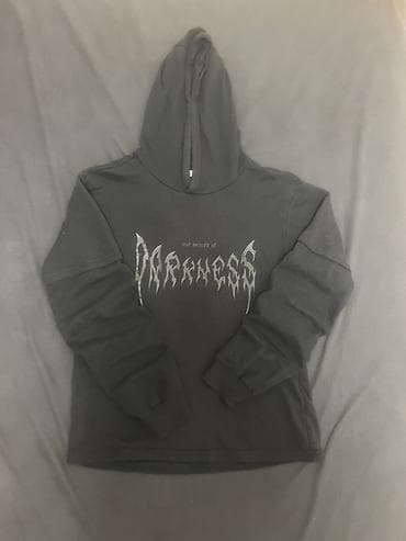 Crna dukserica sa kapuljačom, uniseks kroja. Napred je