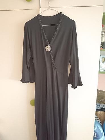 Elegantna duga crna haljina sa rukavima 3/4 i raskošnim detaljima. -