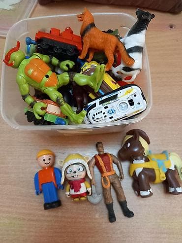 Kolekcija raznovrsnih dečjih figurica i igračaka u plastičnoj kutiji