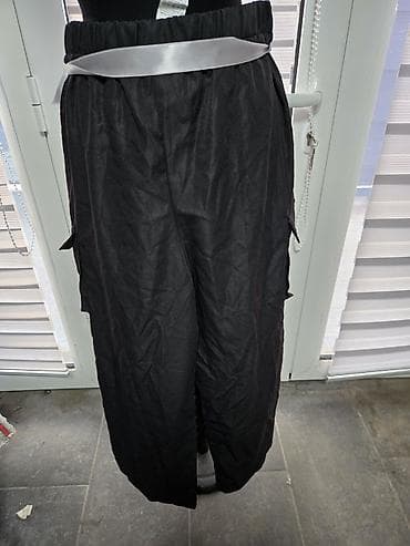 Crne široke pantalone sa elastičnim pojasom i satenskim kaišem. Model na lalafo.rs Crne široke pantalone sa elastičnim pojasom i satenskim kaišem. Model
