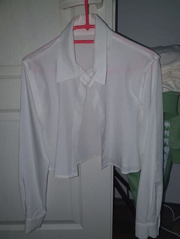 Bela ženska košulja sa dugim rukavima i klasičnim kragnom. Model je na lalafo.rs Bela ženska košulja sa dugim rukavima i klasičnim kragnom. Model je