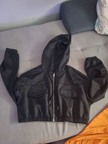 Kratka crna ženska jakna/dukserica sa kapuljačom. Model je crop na lalafo.rs Kratka crna ženska jakna/dukserica sa kapuljačom. Model je crop